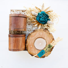 A set of rustic wooden canisters with dry fruits and chocolates, accompanied by a bark slice tea light holder, packaged in a box with a decorative teal rose and a Diwali greeting card.