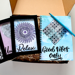 Set of three spiral hardbound diaries with custom messages on them, accompanied by an eco-friendly seed pencil, all displayed in an open corrugated box.