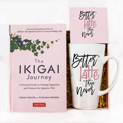 The image features a delightful gift set titled "Better Latte than Never," perfect for expressing appreciation and joy on special occasions. The set includes a beautifully designed book titled "The IKIGAI Journey" by Hector Garcia, which serves as a guide to finding happiness and purpose. Also included are a mug and coaster