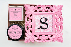 A gift box set including a wooden frame with the letter 'S' on it, a container of bath salts, and bars of soap.
