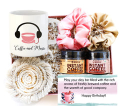 A gift box containing a mug with 'Coffee and Music' text, 2 jars of instant coffee, two satin scrunchies, a macrame coaster, and a birthday card.