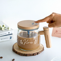 Glass mug with wooden handle and lid, filled with a beverage, on a wooden coaster.