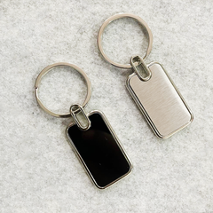 Two keychains with one having a black rectangular tag and the other having a silver rectangular tag.