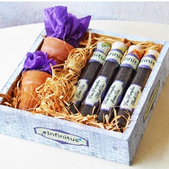 A gift basket containing various packaged tea samplers, with a purple ribbon on top and labels on the individual packages.