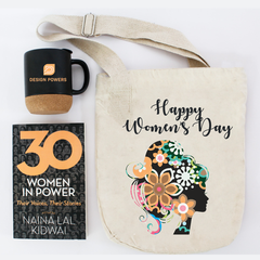 A tote bag with a printed design saying 'Happy Women's Day', a beige ceramic mug with a floral design, and a book titled 'Women in Power' by Naina Lal Kidwai.