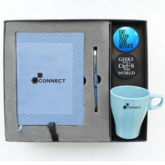 A gift set containing a blue diary, a matching blue pen, a button badge, and a mug, all displayed in a branded box.