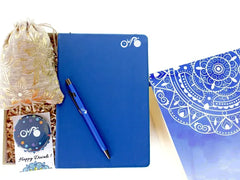 A set of branded stationery which includes a blue notebook, a blue pen, and a custom button badge, presented alongside a pouch of candies, all packaged in a designer-branded gift box.